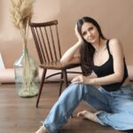 a woman sitting on the floor in front of a wooden chair